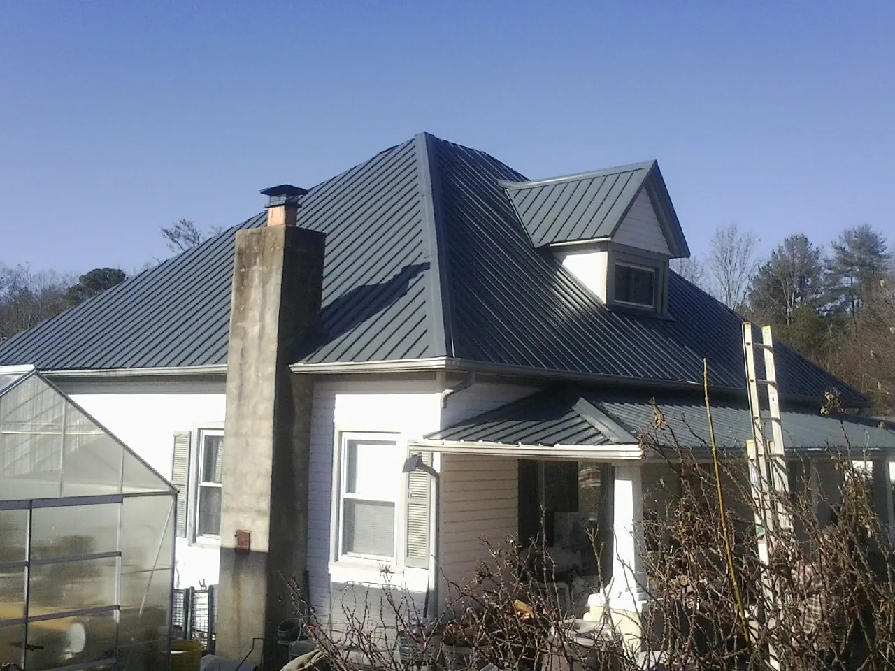 Dark blue standing seam metal roof on a white farmhouse with dormer — Slate & Tile Roof Repair by Roofing Brothers in Servia
