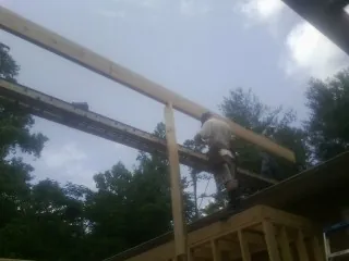 Carpenter setting a ridge beam over a new addition frame — Ice Dam Removal by Roofing Brothers in Servia