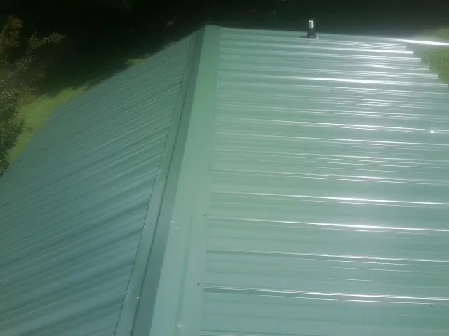 New green metal panels meeting at the ridge of a roof — Flat Roof Repair work by our crew in Servia
