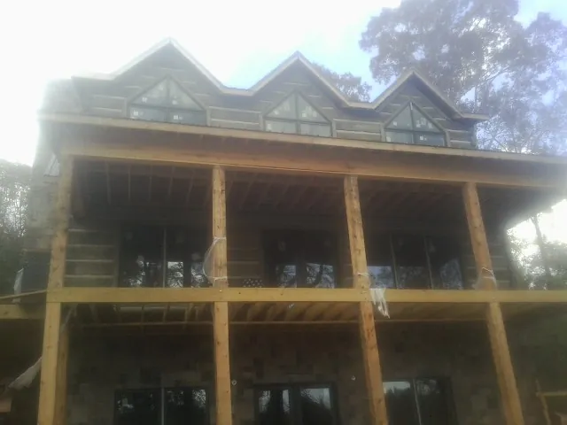 Dormers and porch framing on a large log home under construction — Roof Coating work by our crew in Servia