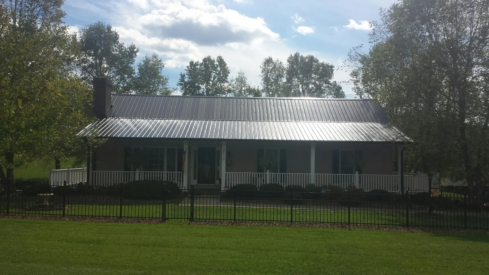 Gray metal roof on a brick ranch with a full width front porch — Gutter Guard Installation work by our crew in Servia