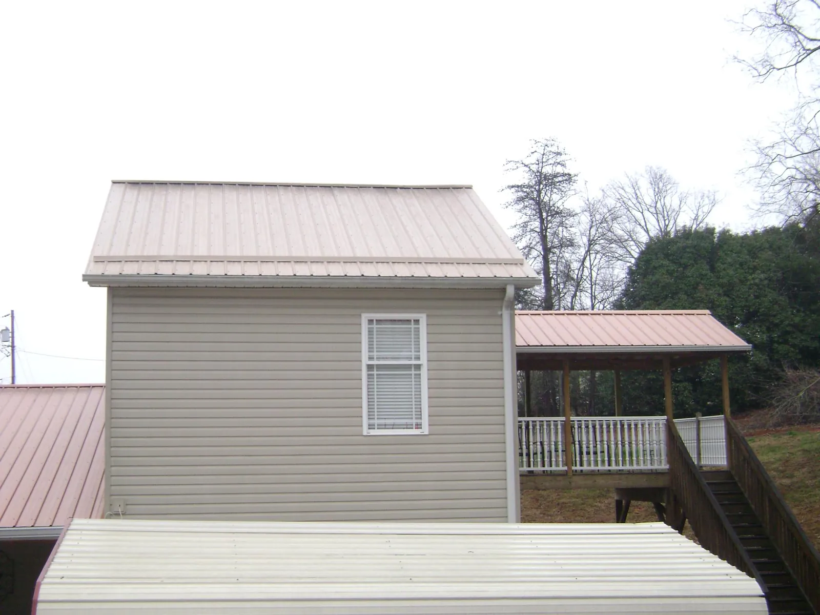 Tan metal roofs on a two story addition and attached porch, from a Roof Replacement job in Servia